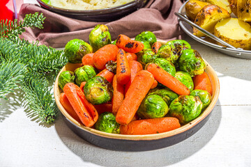 Festive Christmas dinner table with traditional foods and dished – baked ham, chicken, roasted carrots and brussels sprouts, potato, with Christmas decor and gifts 