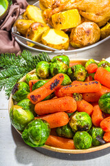 Festive Christmas dinner table with traditional foods and dished – baked ham, chicken, roasted carrots and brussels sprouts, potato, with Christmas decor and gifts 