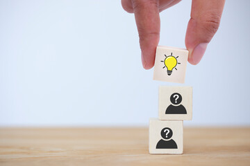 Hand picked wooden cube block, light bulb icon on top of human head icon to show concept creative...