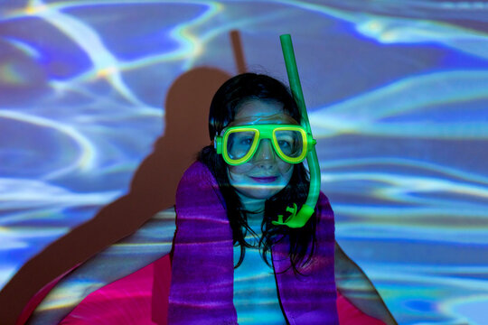 Girl in diving mask near wall with water projection