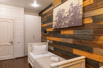 interior of a hotel room with one bed and a wall made of natural wood in warm shades