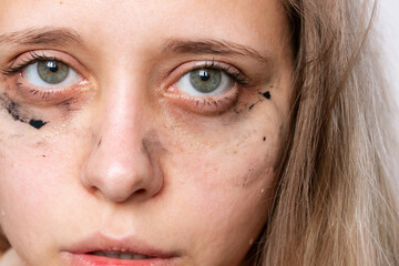 Cropped shot of a young caucasian blonde woman with smeared mascara under her eyes after crying