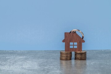 Model of a wooden house on a foundation of coins in piles. The concept of savings and savings to buy a house.