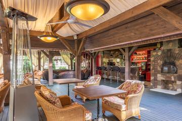 the interior of an outdoor summer cafe without visitors with a bar counter and rattan furniture