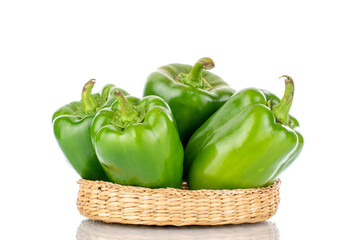 Four sweet green peppers in a straw plate, close-up, isolated on white.