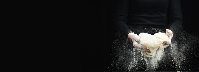 Cooking dough by chef hands for homemade pastry bread with flour splash. On a dark background.