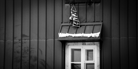 Santa Claus climbing up into a window of moody house. Christmas decoration. Black white histoirc...