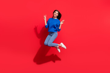 Full body photo of cheerful cool happy woman jump up show v-sign smile isolated on red color background