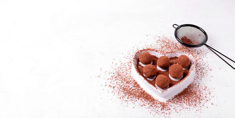 Web banner with chocolate truffles covered in cocoa powder served on the heart shaped plate. Dessert for Valentines Day. Template with copy space on white