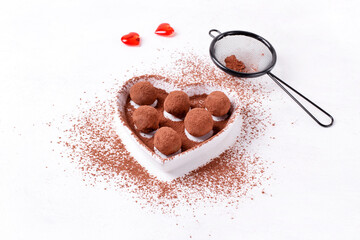 Chocolate truffles covered in cocoa powder served on the heart shaped plate. Dessert for Valentines Day