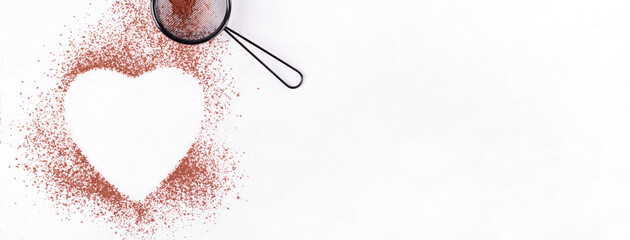 Web banner with cocoa powder framing heart shape and strainer on the white table. Mockup with copy...