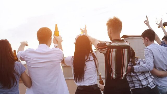 Looking at sundawn together. Group of young people in casual clothes have a party at rooftop together at daytime