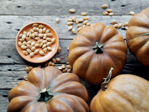 Autumn pumpkin background on a wooden ancient table. Pumpkin harvest with seeds. Photo from above.