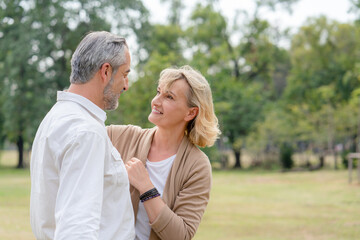 Fototapeta premium Happy couple seniors looking at each other while walking in the park