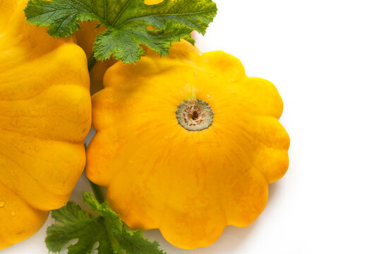 Yellow pattypan squash with green leaf on the white background