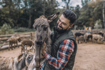 A farmer holding a donkey and smiling