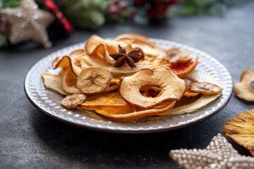 Delicious dried fruit slices of orange, banana, mango, grapefruit, pineapple in a plate with Christmas decorations.