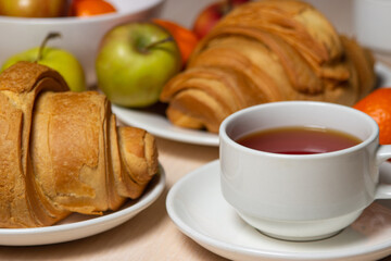 Delicious and healthy breakfast on a white table. A cup of tea with pastries and fruits.