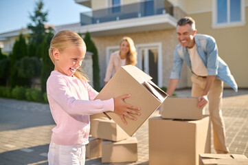 Fototapeta na wymiar Cute family unpacking cardboard boxes while moving to a new house