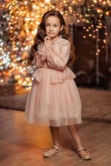Fototapeta na wymiar portrait of a beautiful girl with long hair in an elegant dress at home by the Christmas tree