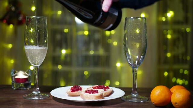 Christmas, holidays. A man and a woman drink champagne from glasses and take sandwiches with red caviar from the table. Hands close-up.