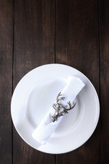 A napkin with a serving ring in the form of a deer head on a white plate. Festive table setting....