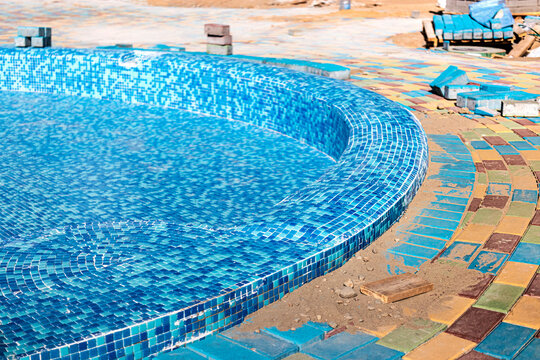 Industrial engineering. Professional tiling in the pool. Installation of blue ceramic pool tiles on cement-concrete floors and walls.