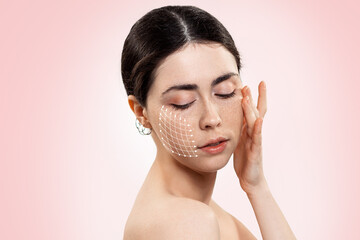 Portrait of a young beautiful woman with a mesh of thread lifting on her face. Pink background