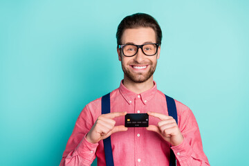 Photo of young business man happy positive smile demonstrate bank plastic card isolated over teal color background