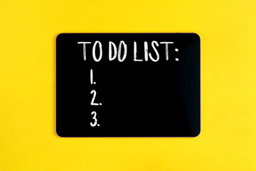 Black digital tablet with to do list on yellow background