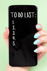 Smartphone with to do list in female hand with beautiful manicure - mint blue nails on green background