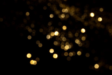Golden blurred bokeh lights on black background. Glitter sparkle stars for celebrate. Overlay for your design