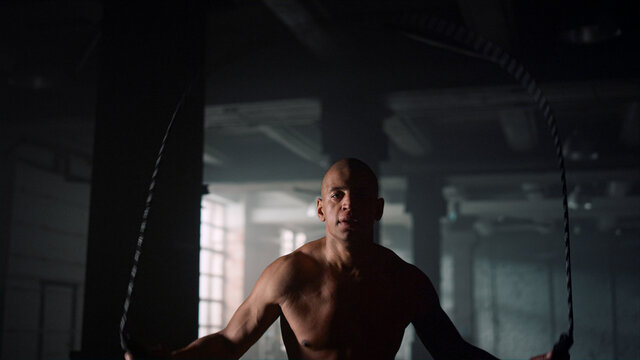 Man jumping with skipping rope in gym. Sportsman doing cardio exercising