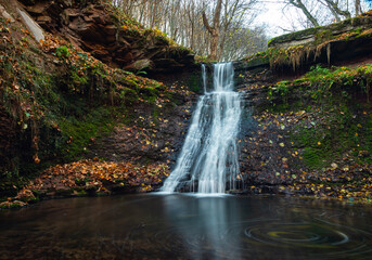 Fototapeta premium Tranquil waterfall scenery in the middle of autumn forest