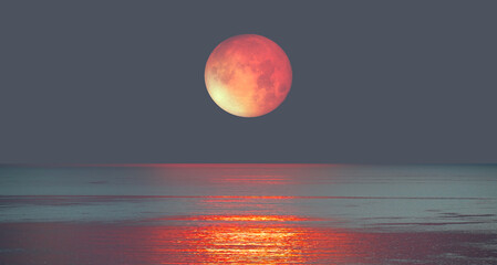 Lunar eclipse over the sea at sunset 