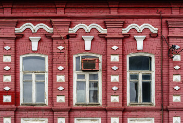 Fototapeta na wymiar Detail of the facade of an old brick building with white wooden window frames and air conditioning. The picture was taken in Russia, in the city of Orenburg
