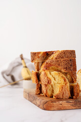 Front view of sliced banana bread on light concrete background, stacked pieces of cake