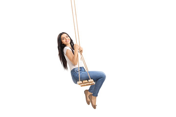 Side shot of a young brunette swinging on a wooden swing and looking at the camera