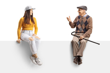 Young female and an elderly man sitting on a blank panel and having a conversation