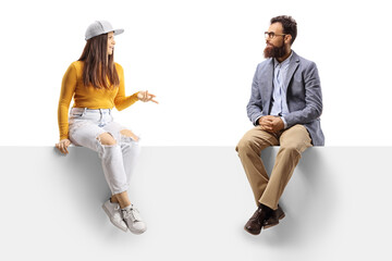 Teen female and a bearded man sitting on a blank panel and having a conversation