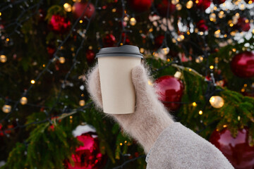Craft paper cup with coffee, cocoa or tea in the hands of a girl against the background of a...
