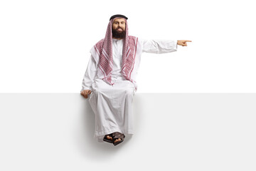 Saudi arab man sitting on a blank panel and pointing