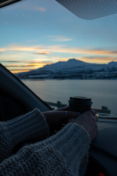 woman watching the sunset in cozy car with mountain landscape and coffee