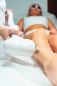 Laser epilation and cosmetology in beauty salon. Laser hair removal, skin care. Unrecognizable master do laser hair removal on woman's legs