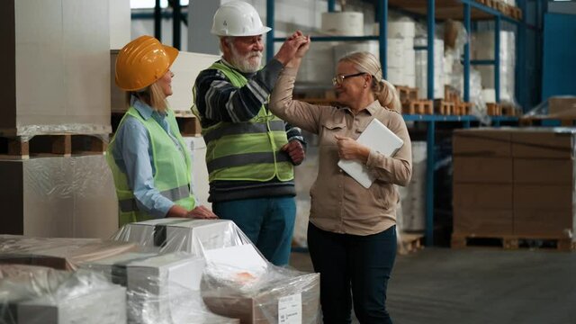 Elderly warehouse worker dancing with colleagues at work in factory 