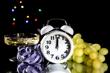 New Year at Midnight. Clock at twelve o'clock with holiday lights and grapes