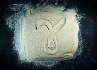 Greek letter gamma written on the white sand with black background