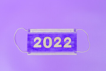 on the lilac medical mask, the numbers 2022 are laid out on a purple background