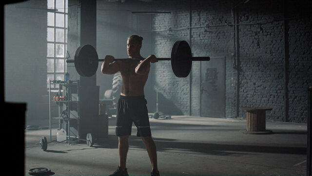 Powerlifter doing weightlifting exercise in gym. Man performing front squat 