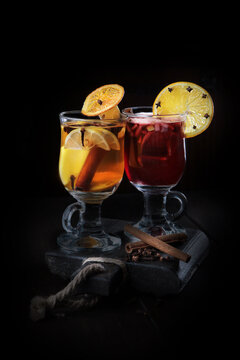 Two glasses with mulled wine on a black background. A hot traditional cocktail of red wine and fruits. Healthy winter drink.Side view. Vertical photo.